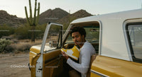 Young Man in Vintage Car with Yellow Sneakers in Desert