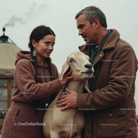 Couple in Warm Attire with Friendly Goat in Rural Setting
