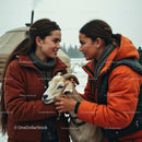 Two Women in Winter Clothing with a Goat in Snowy Setting
