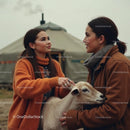 Women in Warm Coats Petting a Goat in a Rural Setting