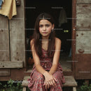 Young Girl Sitting in Front of Rustic Wooden Cabin