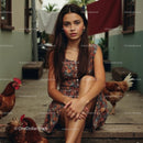 Young Woman in Brown Dress Sitting with Chickens in Backyard