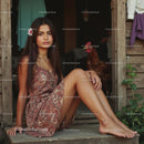 Young Woman in Brown Dress Relaxing on Wooden Porch