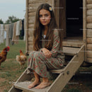 Young Girl in Floral Dress on Rustic Cabin Steps
