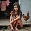 Young Girl in Floral Dress with Chicken at Rustic Farmhouse