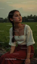 Woman with Braids Relaxing at Sunset in a Tranquil Field