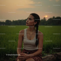 Woman with Braided Hair Sitting on a Log at Sunset