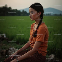 Young Woman with Braids in Green Field at Dusk