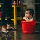 Playful Child in Red Bucket Indoors