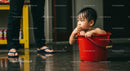 Curious Toddler Enjoying Bath Time in Red Bucket
