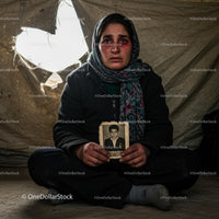 Refugee Woman Holding Old Photograph in Tent Interior