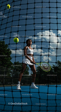 Woman in Action on Tennis Court Under Blue Sky