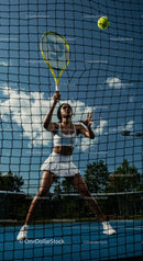 Athletic Woman in Action on Tennis Court with Blue Sky