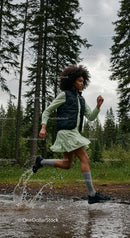 Young Woman Running Through Forest Puddle with Energy
