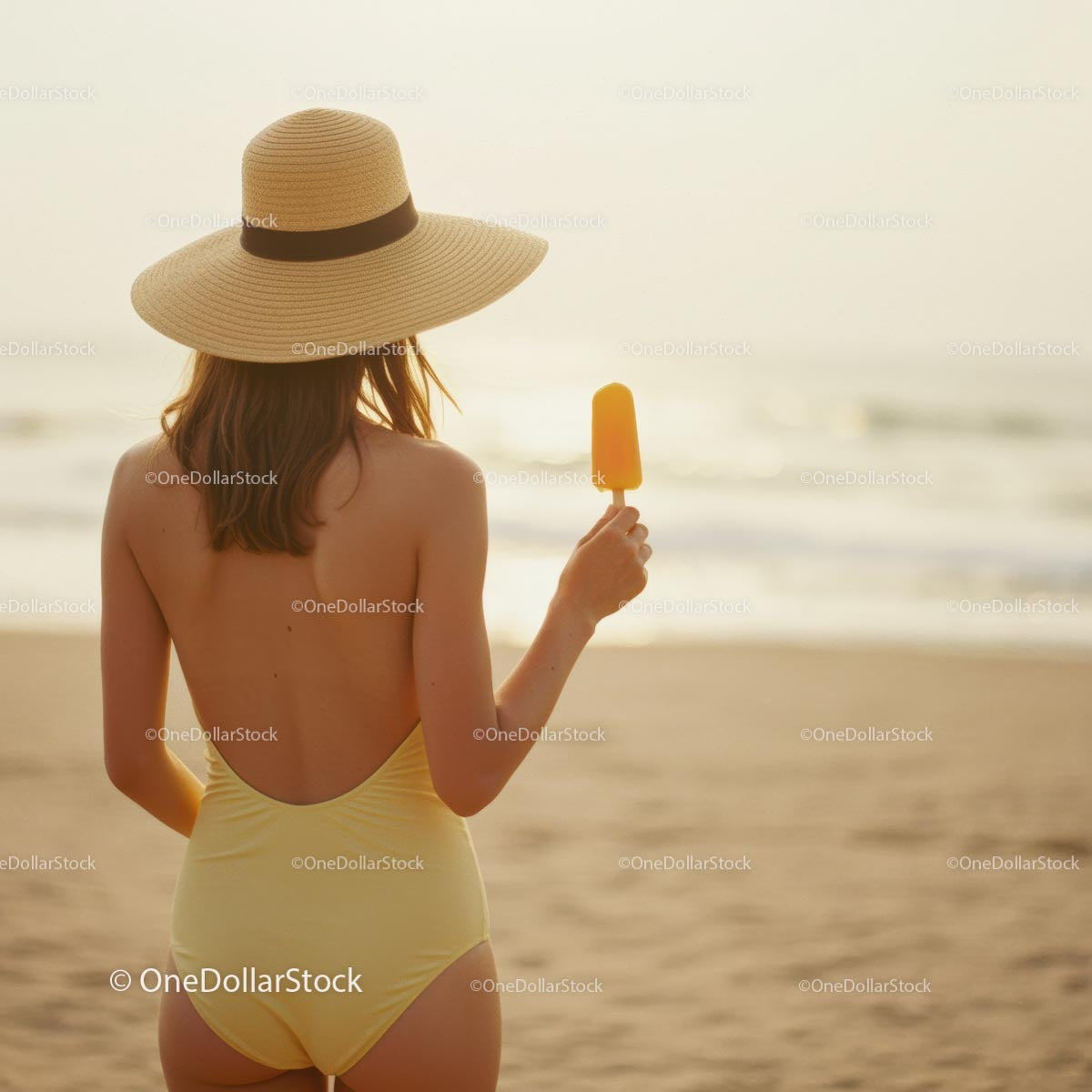 Kobieta w żółtym stroju kąpielowym delektująca się lodami na plaży