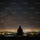Silhouette Under Starry Sky with City Lights Below