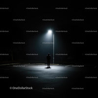 Solitary Figure Under Street Lamp in Dark Parking Lot
