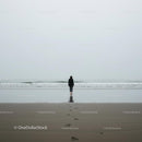 Solitary Figure Walking on Misty Beach at Dawn