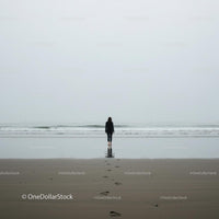 Solitary Figure Walking on Misty Beach at Dawn