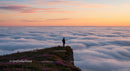 Traveler on a Cliff Overlooking a Sea of Clouds at Sunset