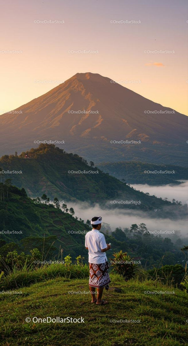 Person in Traditional Attire Overlooking Majestic Volcano