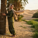 Smiling Woman in Green Jumpsuit Amidst Desert Oasis