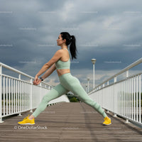 Woman Stretching in Athletic Wear on Outdoor Bridge