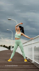 Woman Stretching on Urban Bridge in Green Activewear