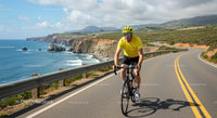 Cyclist Riding Along Scenic Coastal Road with Ocean Views