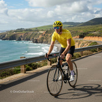 Cyclist in Yellow Riding Along Scenic Coastal Route