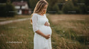 Expecting Mother in White Dress in Grassy Field