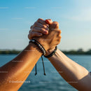 Hands in Unity Against a Clear Blue Sky Over Water