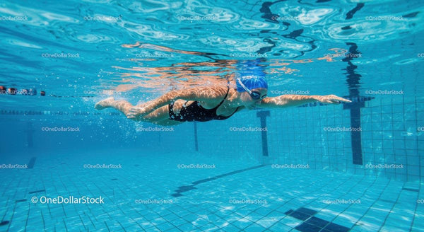 Athlete Gliding Underwater in a Clear Blue Pool