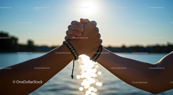 Hands Clasped in Friendship by a Sparkling Lake at Sunset