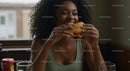 Joyful Woman Savoring a Delicious Burger Indoors