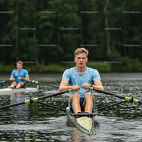 Focused Young Man Rowing on a Calm Lake in Summer