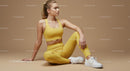 Sporty Woman in Yellow Activewear Sitting on Beige Background