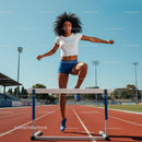 Athletic Woman Hurdling on Stadium Track in Summer