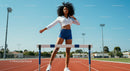 Athletic Woman Training on Outdoor Track with Hurdles