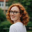 Smiling Woman with Red Hair and Glasses in a Green Setting