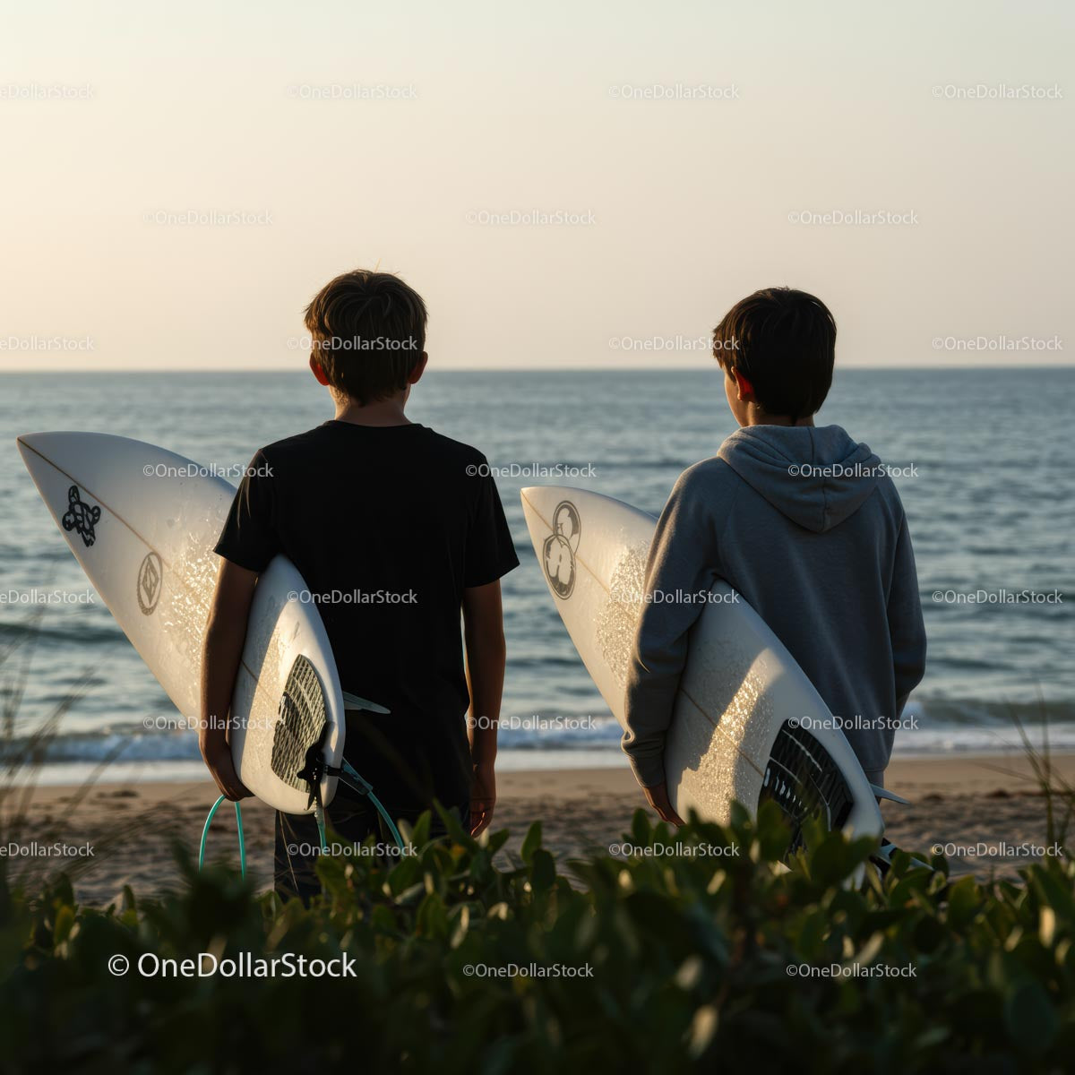Two Young Surfers Watching Sunset by the Ocean