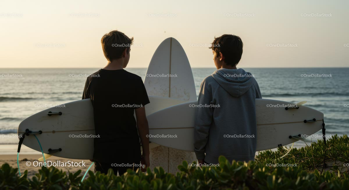 Two Boys with Surfboards Watching Ocean Sunset