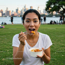 Woman Enjoying a Meal in an Urban Park with City Skyline