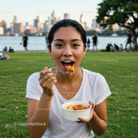 Woman Enjoying a Meal in an Urban Park with City Skyline