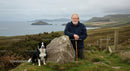 Elderly Man with Border Collie in Scenic Coastal Landscape