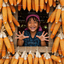 Joyful Girl Amidst Hanging Corn in Rustic Setting