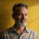 Smiling Mature Man in Floral Shirt Against Yellow Background