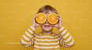Playful Child Holding Orange Slices in Yellow Background