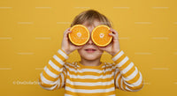 Playful Child Holding Orange Slices in Yellow Background