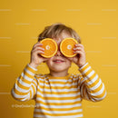 Playful Child Holding Orange Slices Against Yellow Background
